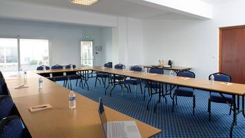A conference room with a long table, chairs, a laptop, water bottles, and a door.