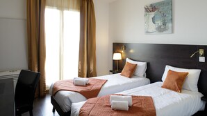 A hotel room with two beds, a desk, and a chair.