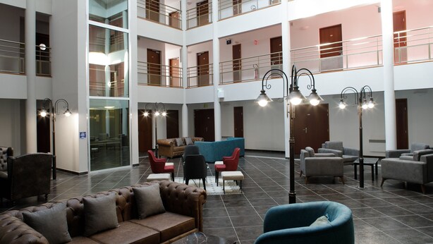 A spacious lobby with a high ceiling, multiple seating areas, and a central coffee table.
