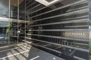 A modern building facade with a glass entrance and a sign that reads 'LEGENDAL SHINSAIBASHI-EAST'.