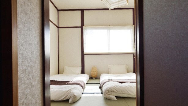 A traditional Japanese-style room with tatami flooring, two single beds, a shoji screen, and a small woven basket on the floor. - USJ / Quiet Private Japanese Traditional House,  close to Osaka fish market! (Osaka)