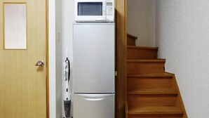 A kitchen with a white refrigerator and microwave, a wooden door, and a wooden staircase. - USJ / Quiet Private Japanese Traditional House,  close to Osaka fish market! (Osaka)