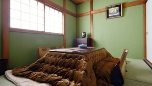 A room with a bed covered in a brown blanket, a wooden headboard, a window with blinds, a small table with a vase and a picture frame, and a green wall. - USJ / Quiet Private Japanese Traditional House,  close to Osaka fish market! (Osaka)
