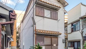 A residential building with a tiled roof, a visible balcony, and a small garden area with potted plants. - USJ / Quiet Private Japanese Traditional House,  close to Osaka fish market! (Osaka)