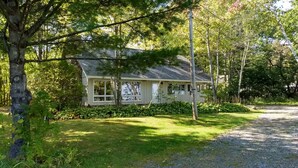 A house with a sloped roof, surrounded by a well-maintained lawn and dense trees. - Waterfront Home with large pond (Belgrade)