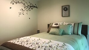 A bedroom with a bed, pillows, a wall decoration, and a framed picture. - Waterfront Home with large pond (Belgrade)