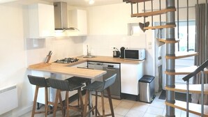 A modern kitchen with a central island, bar stools, a microwave, and a dishwasher.