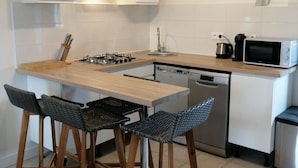 A modern kitchen with a central island, bar stools, a microwave, and a dishwasher.