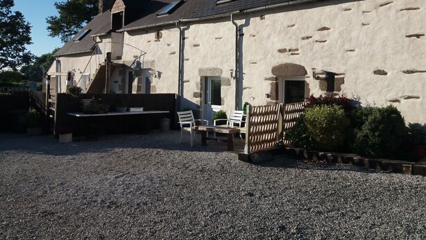 A stone building with a gravel driveway, outdoor seating, and a wooden fence.