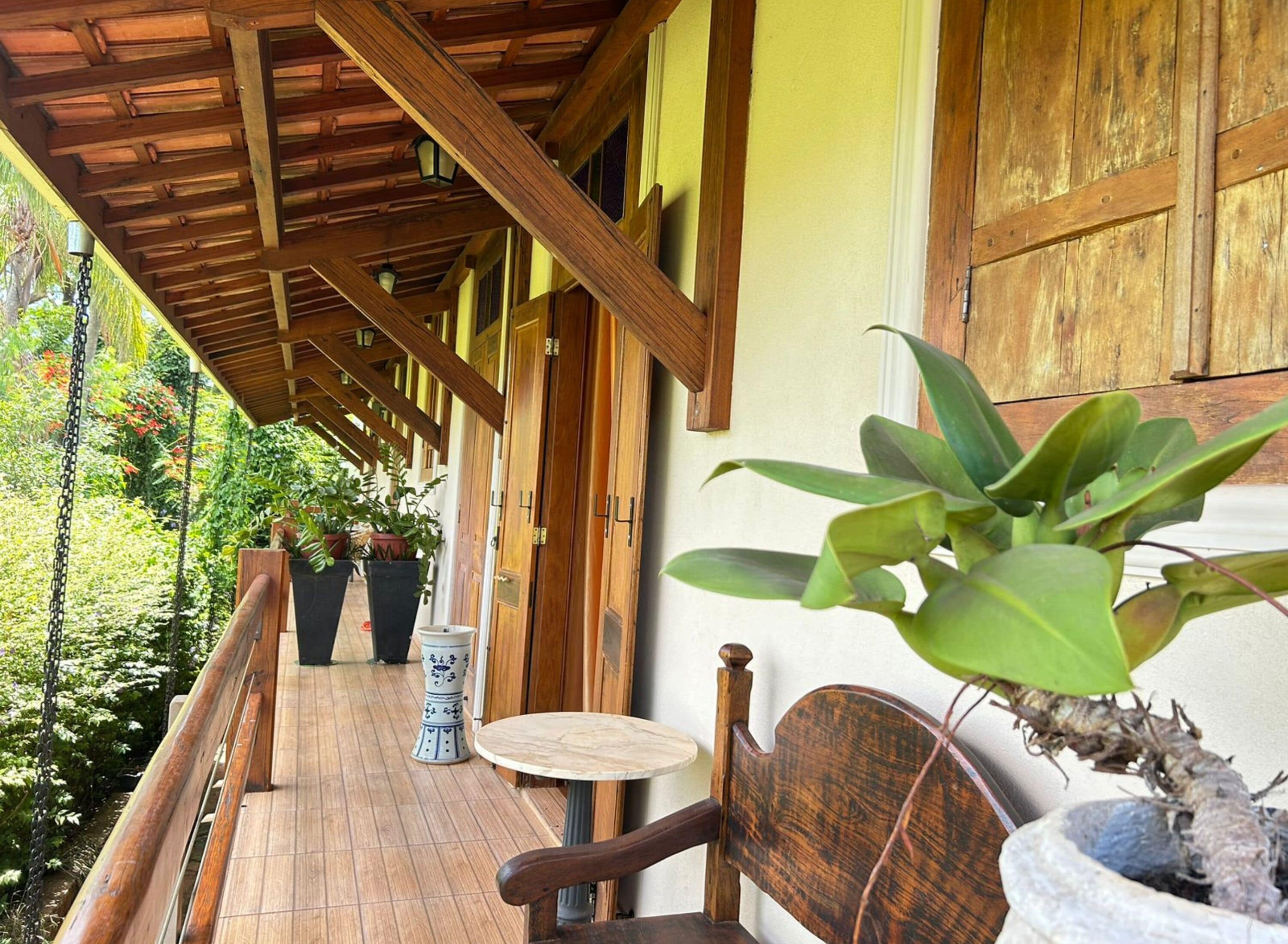 A wooden deck with a covered area, potted plants, and a table and chair.