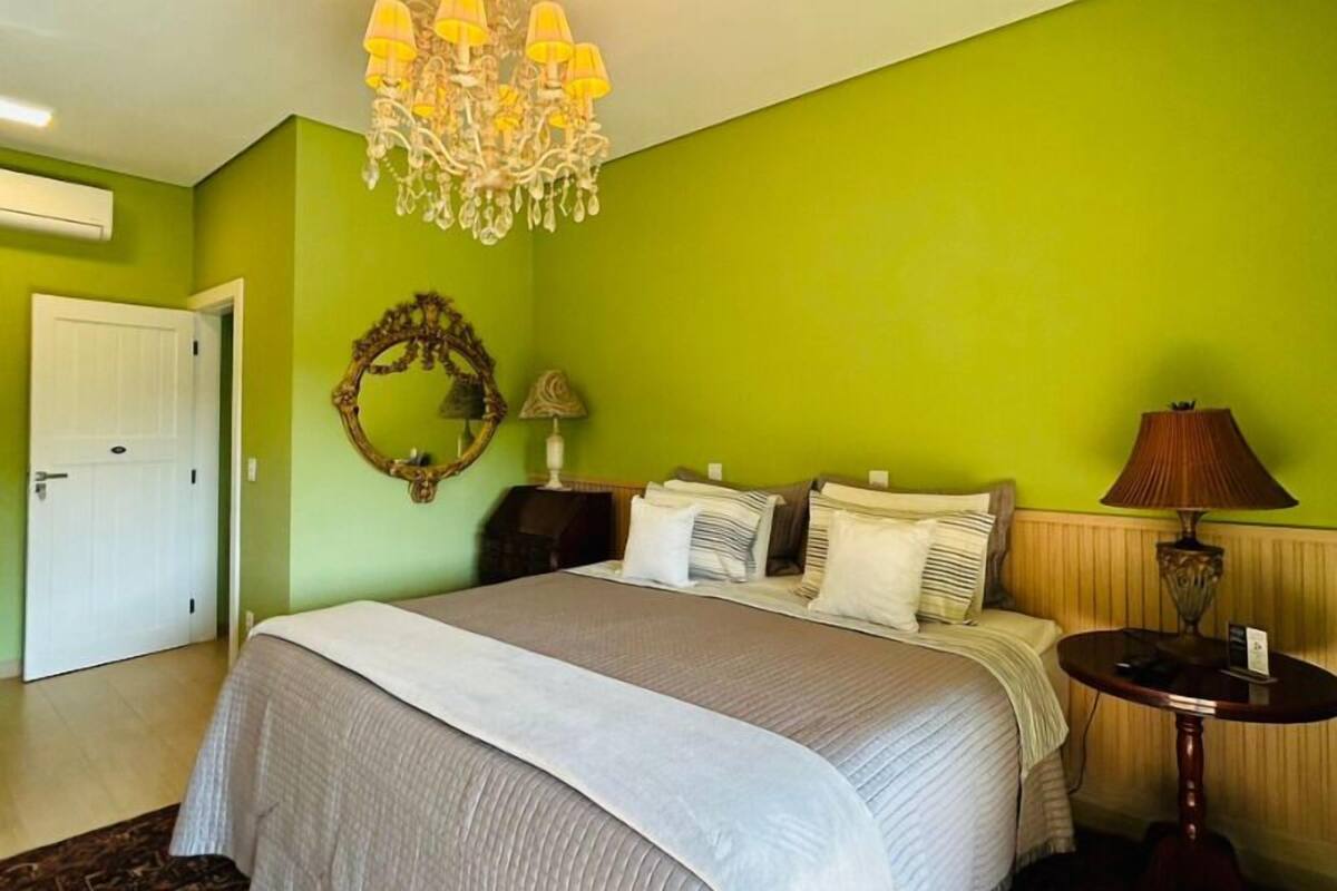 Ein Schlafzimmer mit einem großen Bett, einem Kronleuchter, einem Spiegel und einer Lampe.