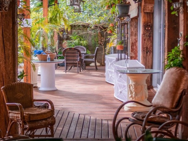 An outdoor patio area with wicker chairs, a round table, and potted plants.