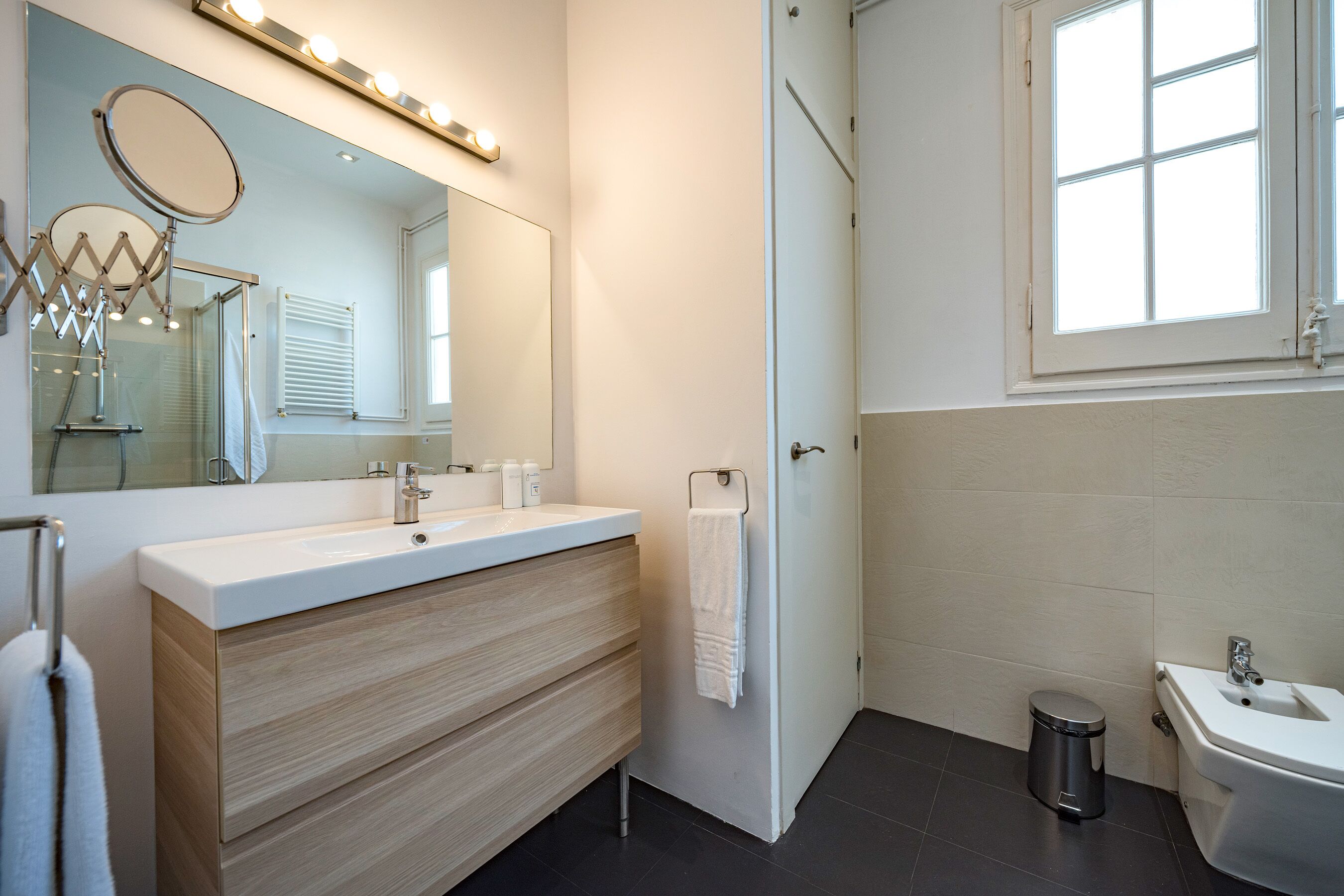 Un bany modern amb un lavabo, mirall i un rentapans separat.