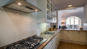 Una cocina moderna con estufa a gas, armarios blancos y un amplio ventanal que proporciona luz natural.