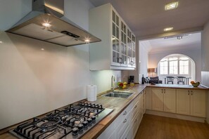 A modern kitchen with a gas stove, white cabinets, and a window providing natural light.