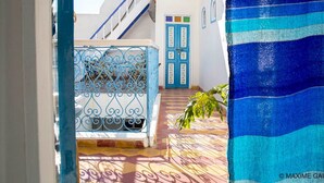A narrow alleyway with a blue gate, white buildings, and a staircase. - Hotel Emeraude Essaouira (Essaouira)