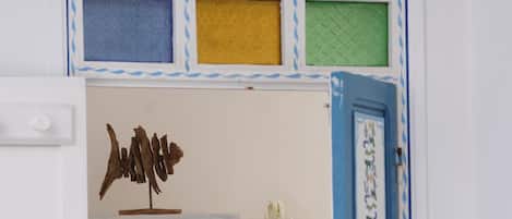 A room with a white door, a blue-framed window, and a wall-mounted decorative piece.
