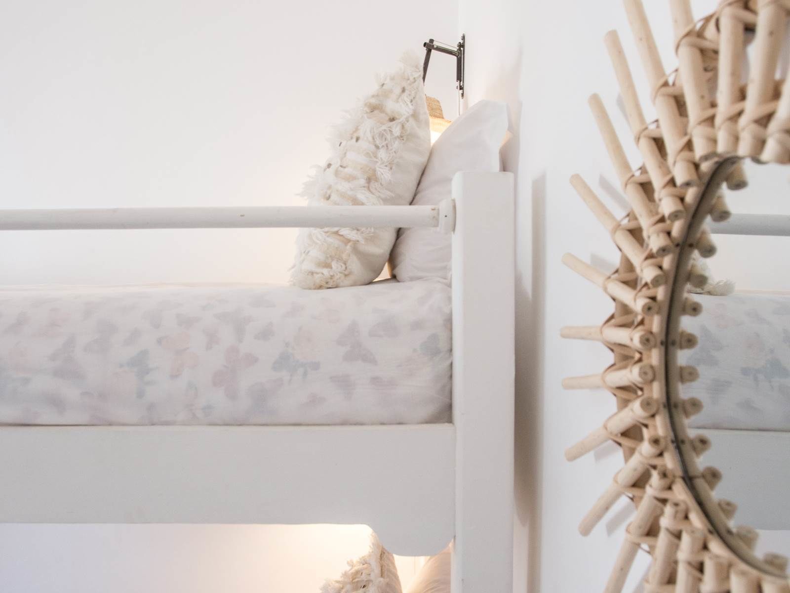 A bunk bed with a white frame and a decorative wall hanging.