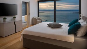 Une chambre moderne avec un grand lit, une télévision et une vue sur la mer.