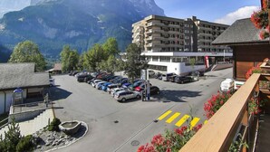 A parking lot with cars, a building with balconies, and a mountain in the background. - Chalet Abendrot apARTments by Interhome (Grindelwald)