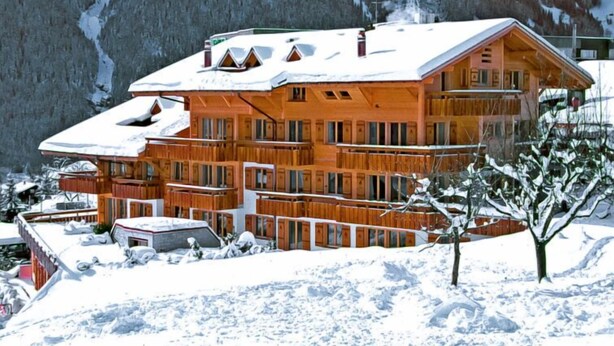 A multi-story wooden chalet with balconies, surrounded by snow-covered mountains. - Chalet Abendrot apARTments by Interhome (Grindelwald)