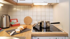 A kitchen with a stove, a kettle, a bread box, and a cork coaster. - Chalet Abendrot apARTments by Interhome (Grindelwald)