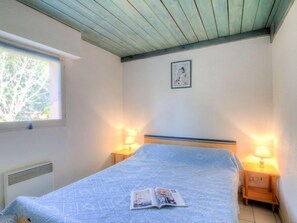 A bedroom with a bed, two bedside lamps, a window, and a wall-mounted picture. - Le Gallia by Interhome (Capbreton)