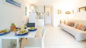 Ett kompakt bostadsutrymme med en matplats, ett litet kök och en soffa.