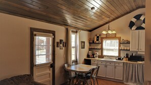 A kitchen with wooden ceiling, a dining table with chairs, a kitchen island, and a refrigerator. - Welcome to Pearl Haven - a 500 sf gem! Hosting both Long and Short-term rentals! (Camden)