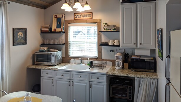 A kitchen with a sink, microwave, toaster, and cabinets. There is a sign above the sink that reads "Captain's Quarters". - Welcome to Pearl Haven - a 500 sf gem! Hosting both Long and Short-term rentals! (Camden)