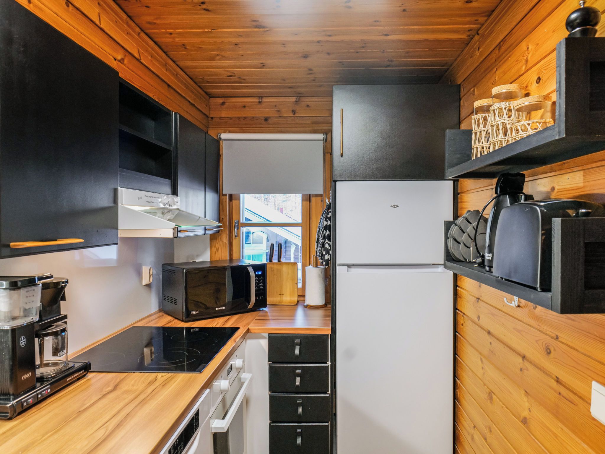 A compact kitchen with a microwave, coffee maker, and a refrigerator.