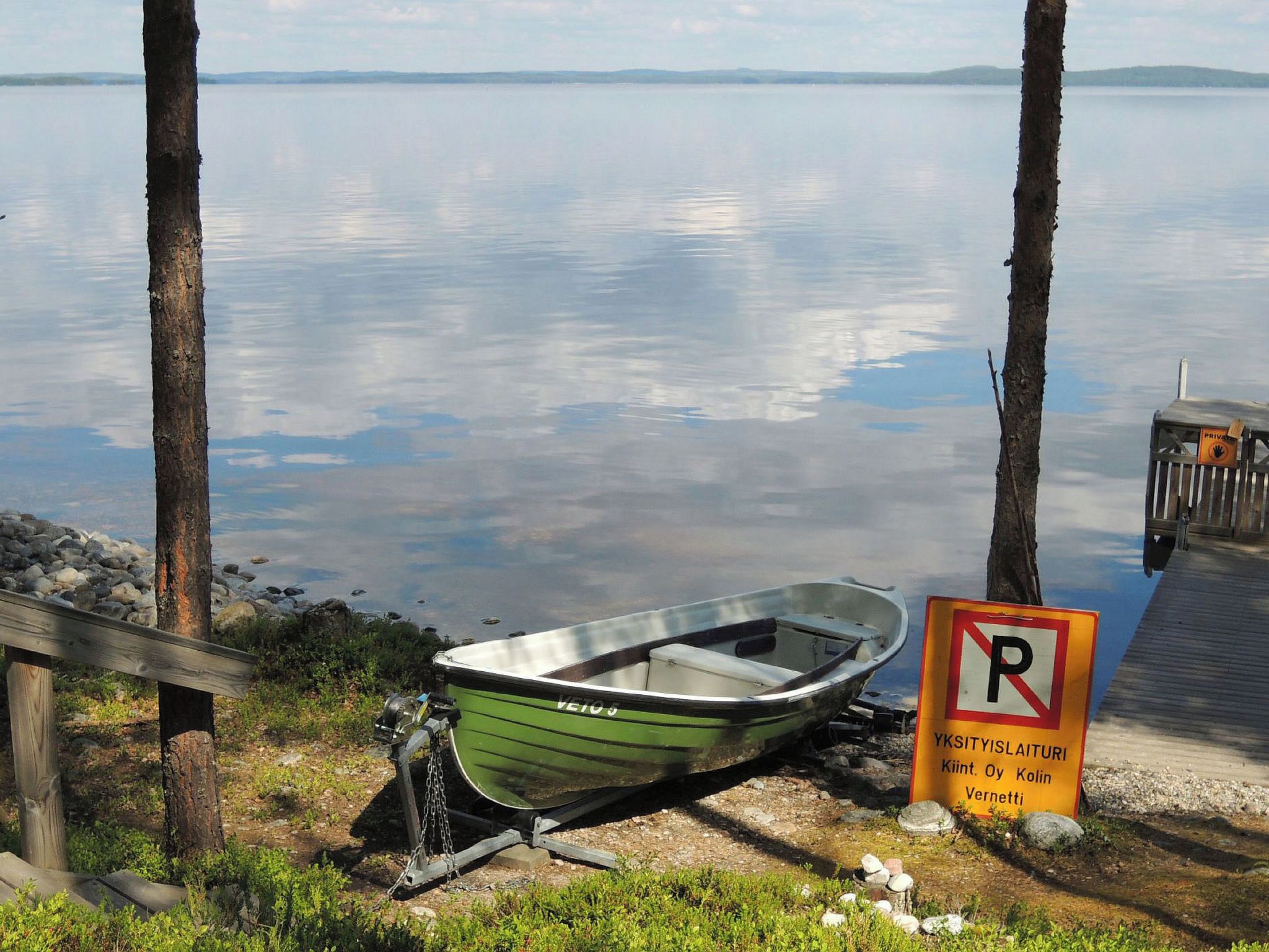 A green boat tied to a dock with a no parking sign nearby.