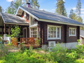 A log cabin with a porch, large windows, and a chimney.