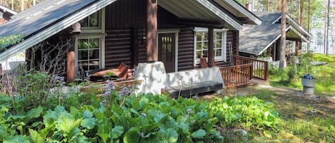 Een blokhut met een veranda, omringd door weelderige begroeiing.