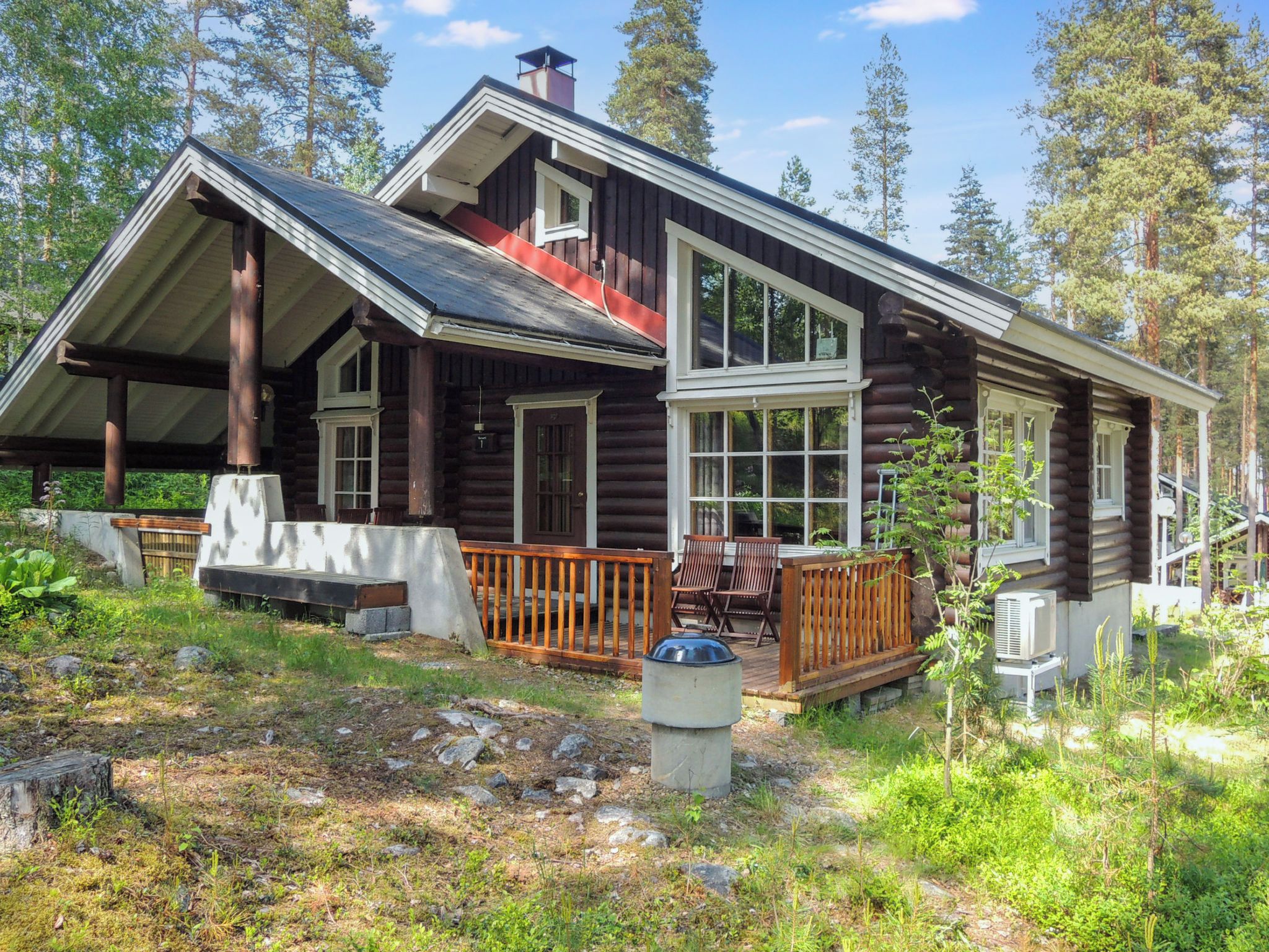 A log cabin with a porch, large windows, and a chimney.