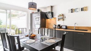 Una cucina moderna con mobili scuri, un piano di lavoro in legno e un'area pranzo con tavolo e sedie neri.