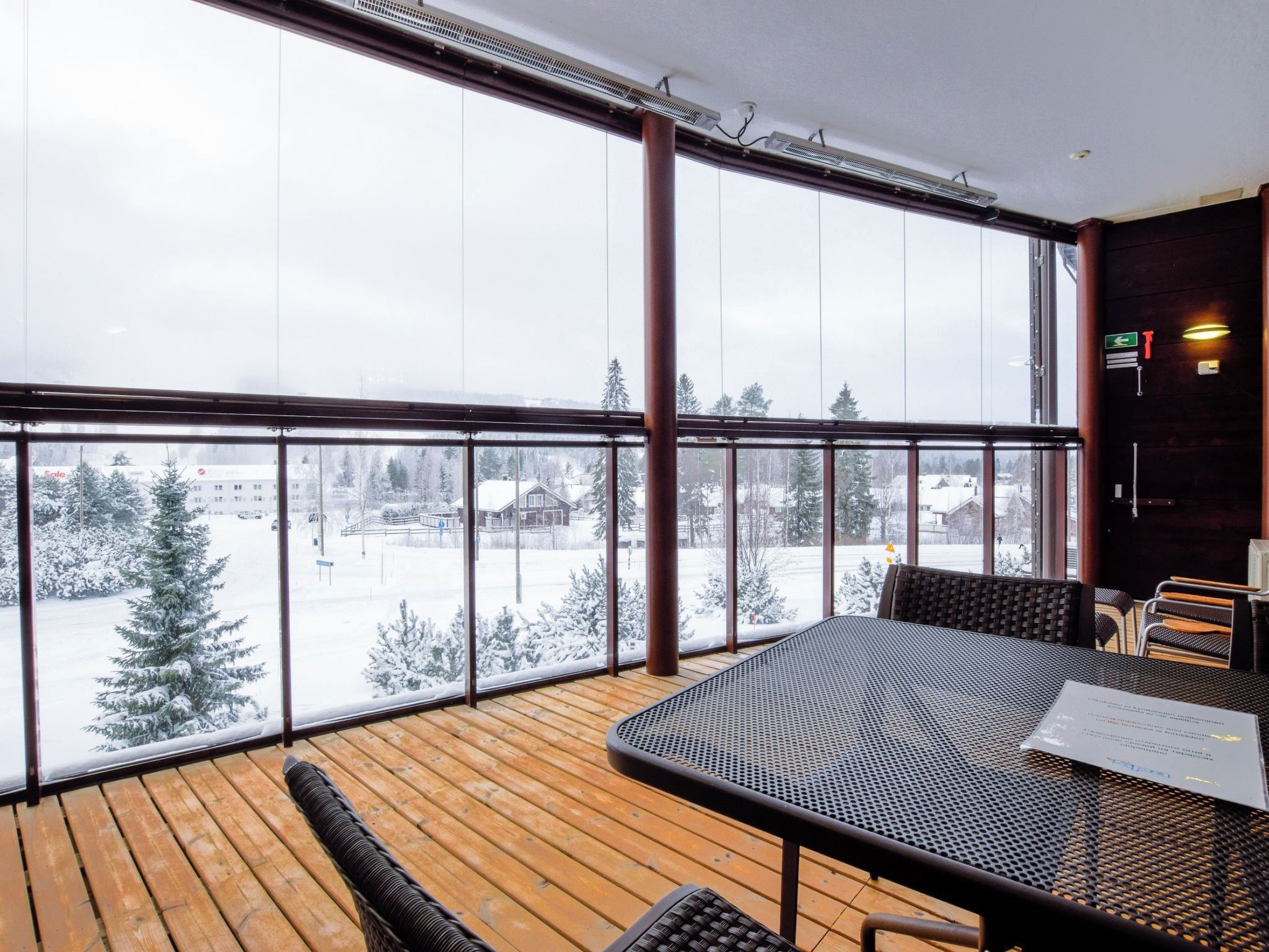 Un balcone con pavimento in legno, ringhiera in metallo e un tavolo con sedie.