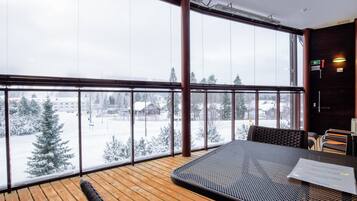 Un balcone con pavimento in legno, ringhiera in metallo e un tavolo con sedie.