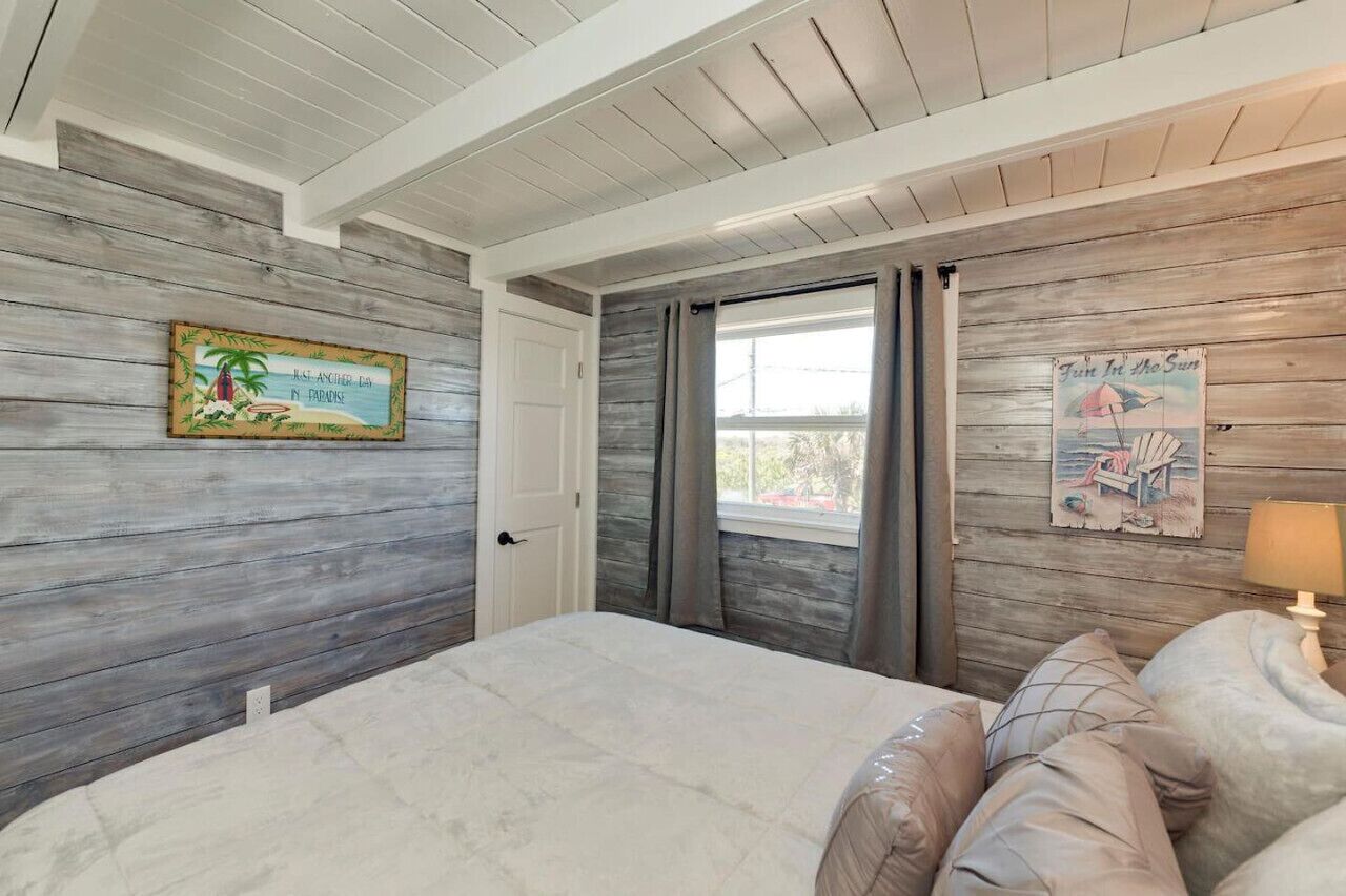 A bedroom with a bed, a door, and a window with curtains.
