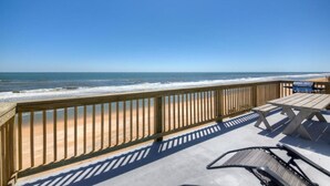 A wooden deck with a view of the beach and ocean.