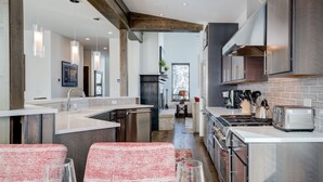 Una cocina moderna con una isla central, electrodomésticos de acero inoxidable y un comedor con sillas de estampado rojo y blanco.