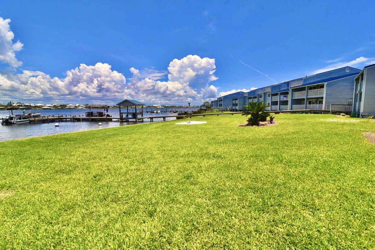 A hotel with a grassy lawn, a dock, and a body of water.