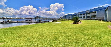 A hotel with a grassy lawn, a dock, and a body of water.