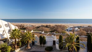 Een kustgezicht met een strand, palmbomen en moderne architectuur.