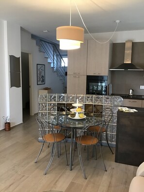 Une cuisine moderne dotée d’un îlot central, d’appareils électroménagers en acier inoxydable et d’un escalier menant à un autre niveau.