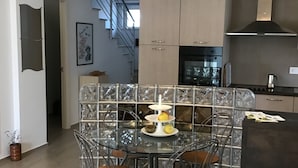 Een moderne keuken met een centraal eiland, roestvrijstalen apparatuur en een trap naar een hoger niveau.