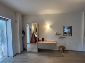 A modern interior with a mirrored wardrobe, a bedside table, a wall-mounted light, and a framed picture.