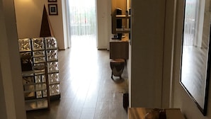 Een gang met een houten vloer, een glazen kast en een deur naar een balkon.