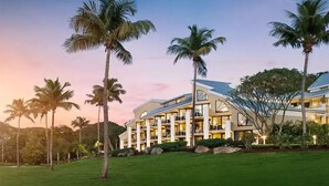 A modern hotel with a multi-story structure, large windows, and a well-maintained lawn with palm trees. - Westin St. John 3BR, 3BA Pool Villa  - Christmas Week 2026 - Dec. 20-27, 2026 (Cruz Bay)