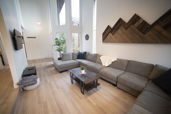 Una sala de estar moderna con un sofá modular, una mesa de centro y un televisor montado en la pared.